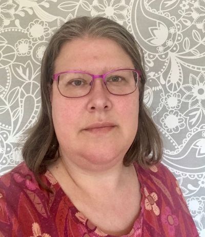 Tina Wiman Tina Wiman i lila glasögon och hår till axlarna mot en bakgrund av grått med vita skissade figurer.